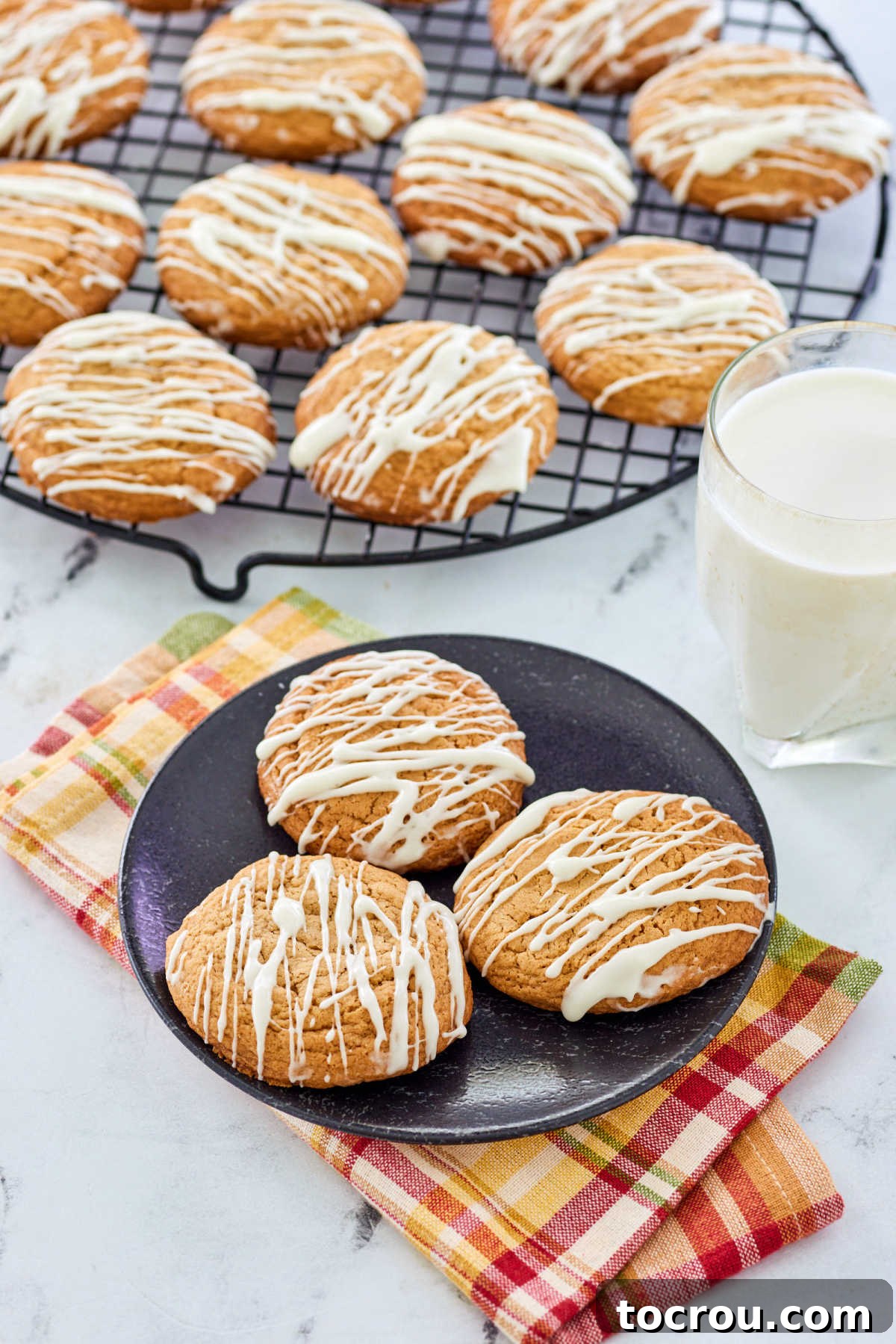 Glazed Cookies and Milk Plate of maple cinnamon cookies drizzled with a white powdered sugar glaze next to a glass of milk, ready to enjoy.
