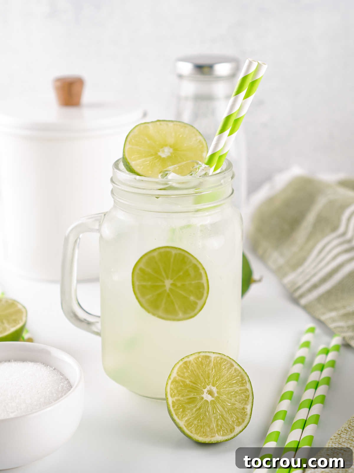Glass jar filled with lime shake up mixture and ice, ready to drink.