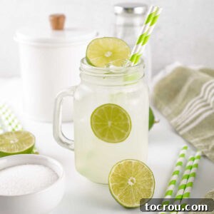 Glass jar filled with lime shake up mixture and ice, ready to drink.