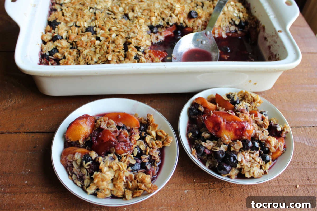 Individual Servings of Blueberry Peach Crisp Small dishes filled with warm blueberry peach crisp with oat topping.