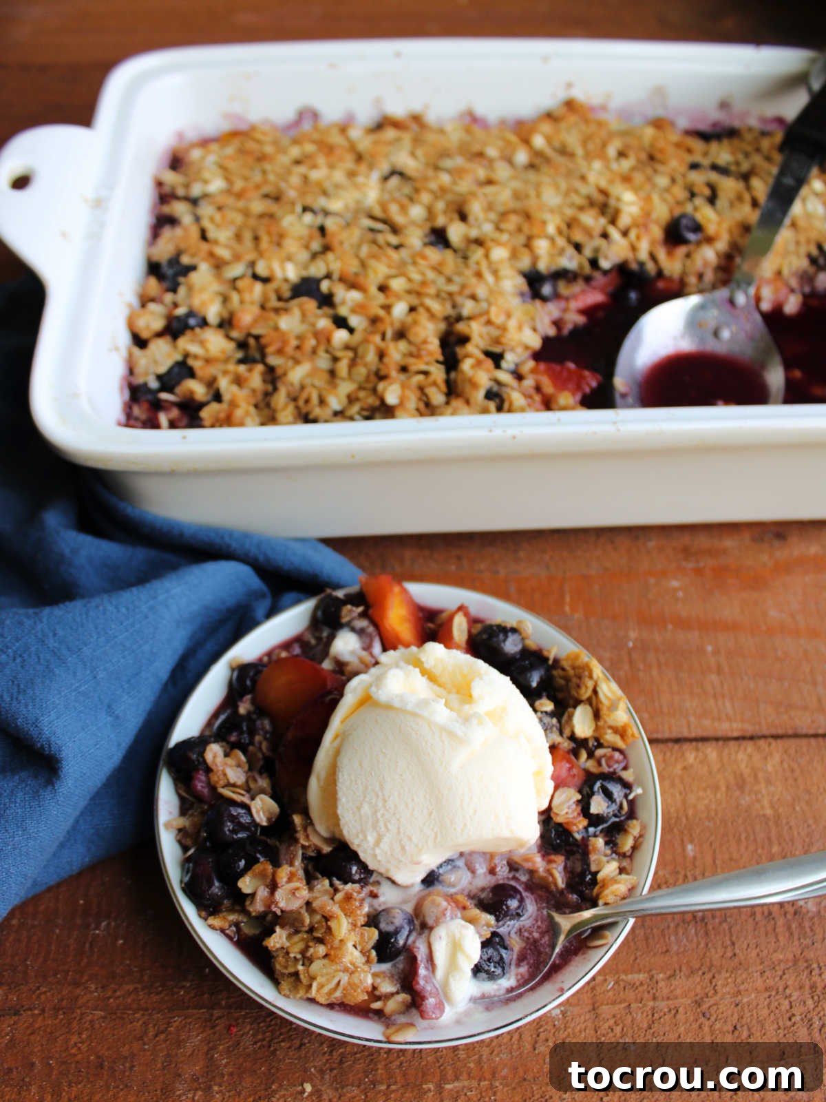 A Spoonful of Heaven: Crisp and Ice Cream Bite of peach blueberry crisp on spoon with vanilla ice cream.