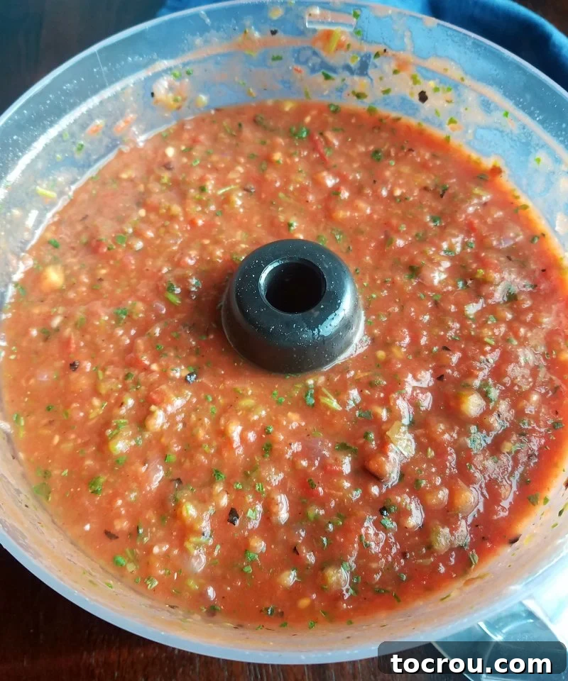 Salsa in Food Processor A food processor filled with freshly made roasted salsa, showing its chunky texture and inviting color.