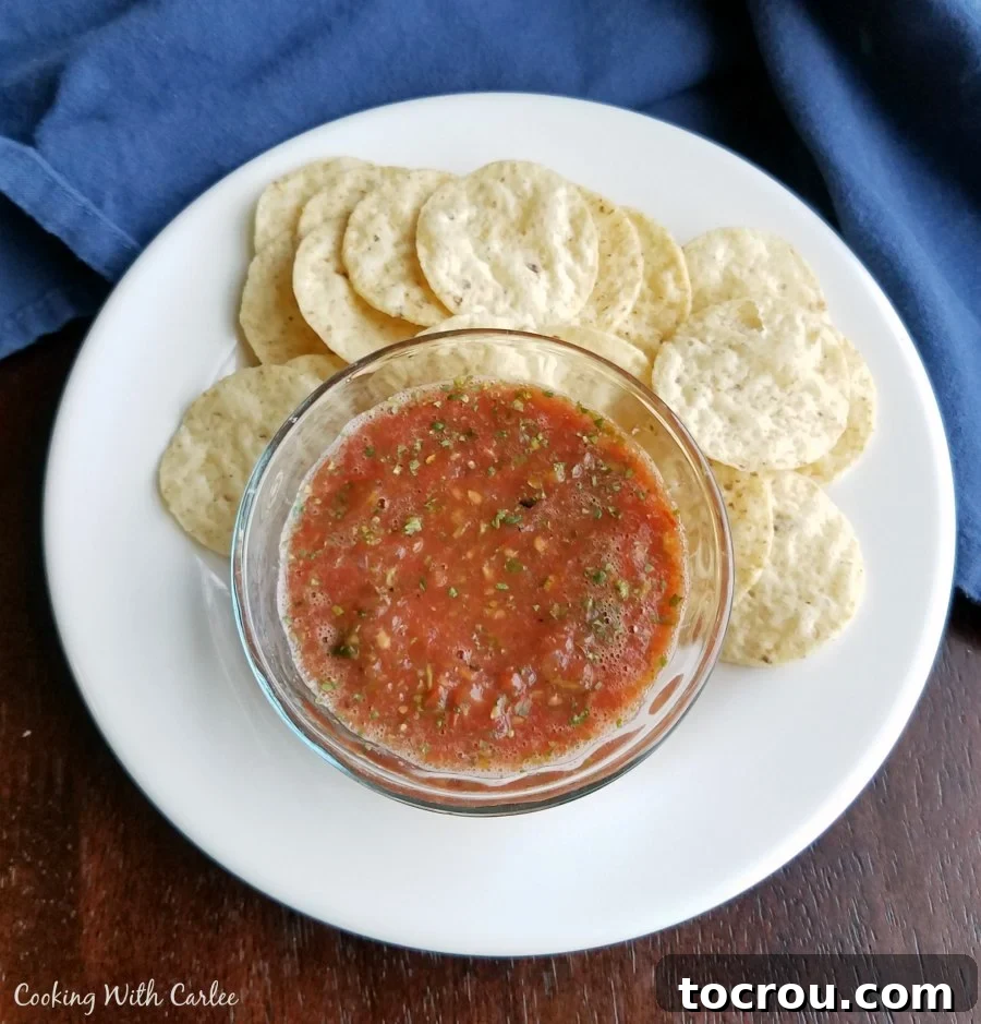 Salsa with Chips A bowl of homemade roasted salsa on a plate surrounded by tortilla chips, ready for serving.