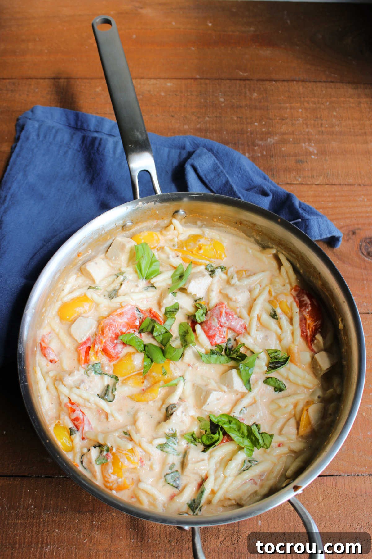 Pan filled with baked feta pasta with tomatoes, basil, and chicken, ready to serve.