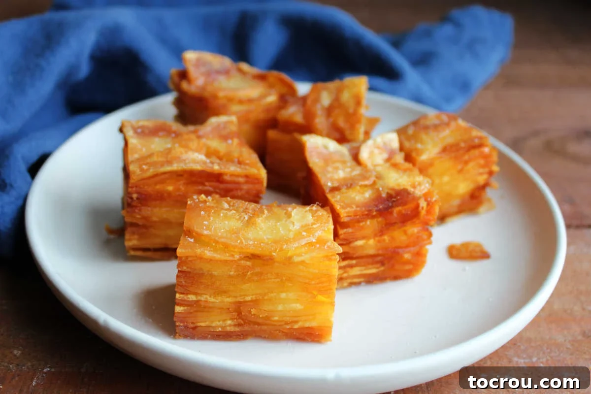 Plate of golden brown thousand layer potatoes (stacked thinly sliced potato cubes fried until crispy on the outside) topped with truffle salt.