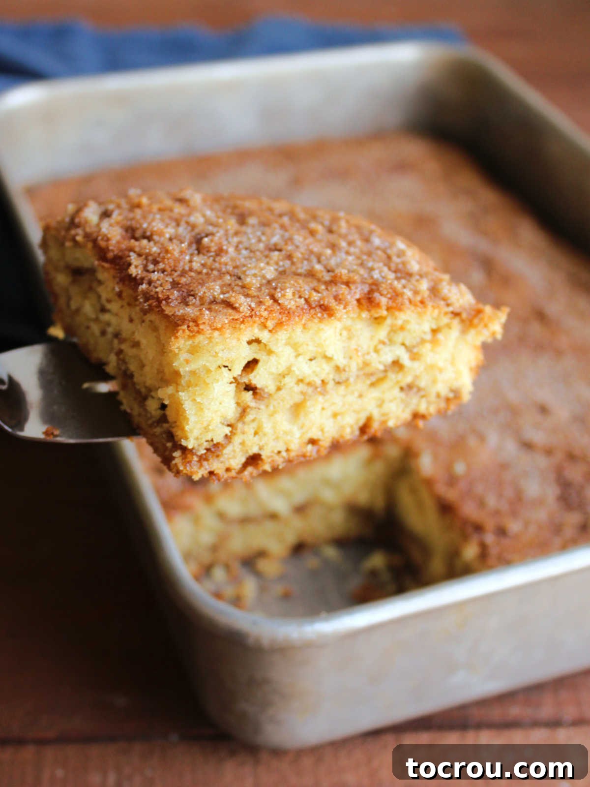 Serving Sour Cream Coffee Cake Spatula lifting a piece of sour cream coffee cake out of a 9x13-inch pan.