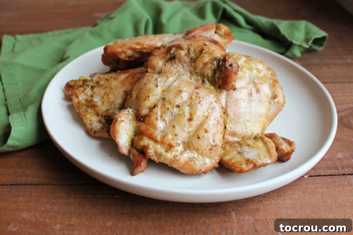 Platter of golden-brown coconut lime chicken thighs, fresh off the pellet grill, garnished with fresh lime wedges and cilantro, ready to be served.