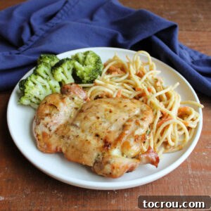 Dinner plate with grilled coconut lime chicken thigh, peanut noodle salad, and steamed broccoli, ready to eat.