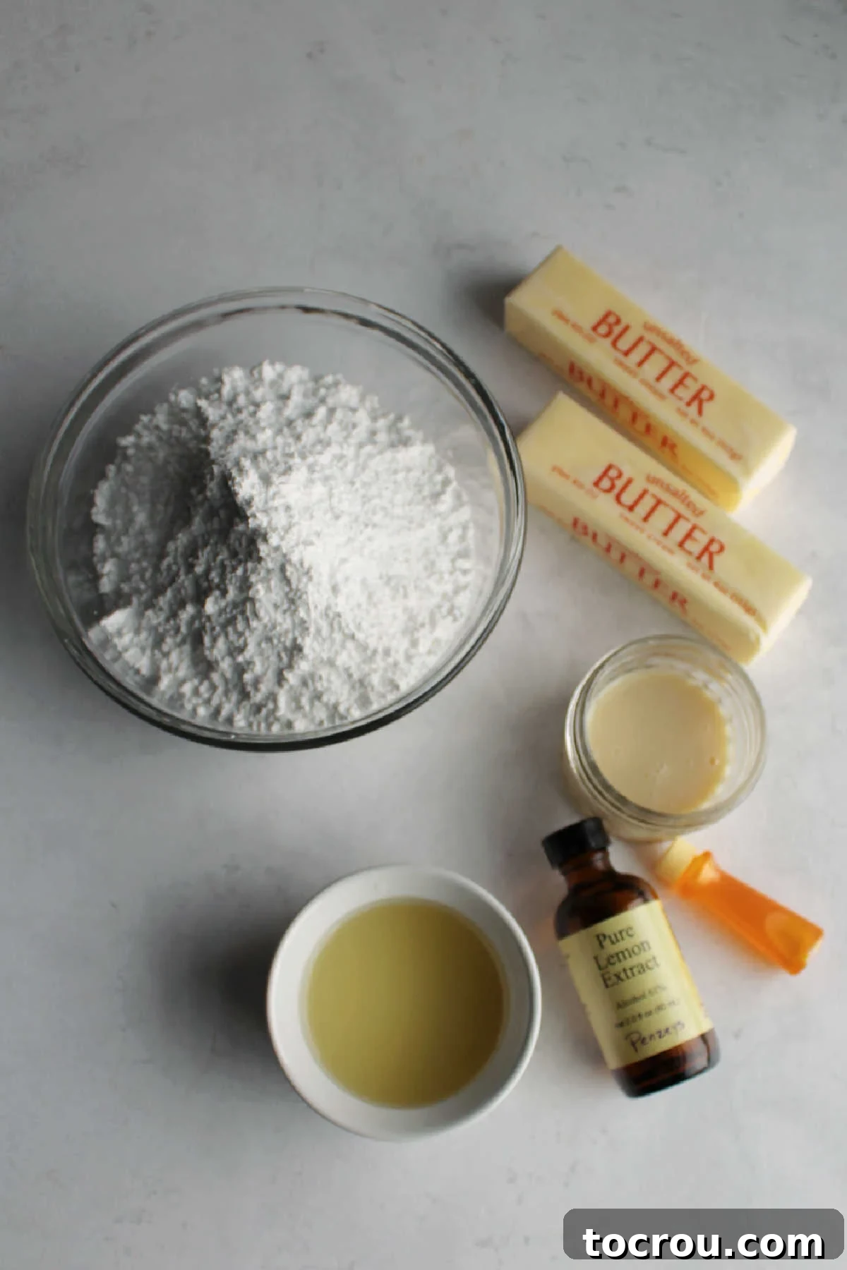 Essential Ingredients for Lemon Buttercream A vibrant display of fresh, high-quality ingredients, including softened unsalted butter, a generous mound of powdered sugar, fresh lemon juice, aromatic lemon extract, and a can of luscious sweetened condensed milk, all meticulously arranged and ready to be transformed into an exquisite lemon buttercream frosting.