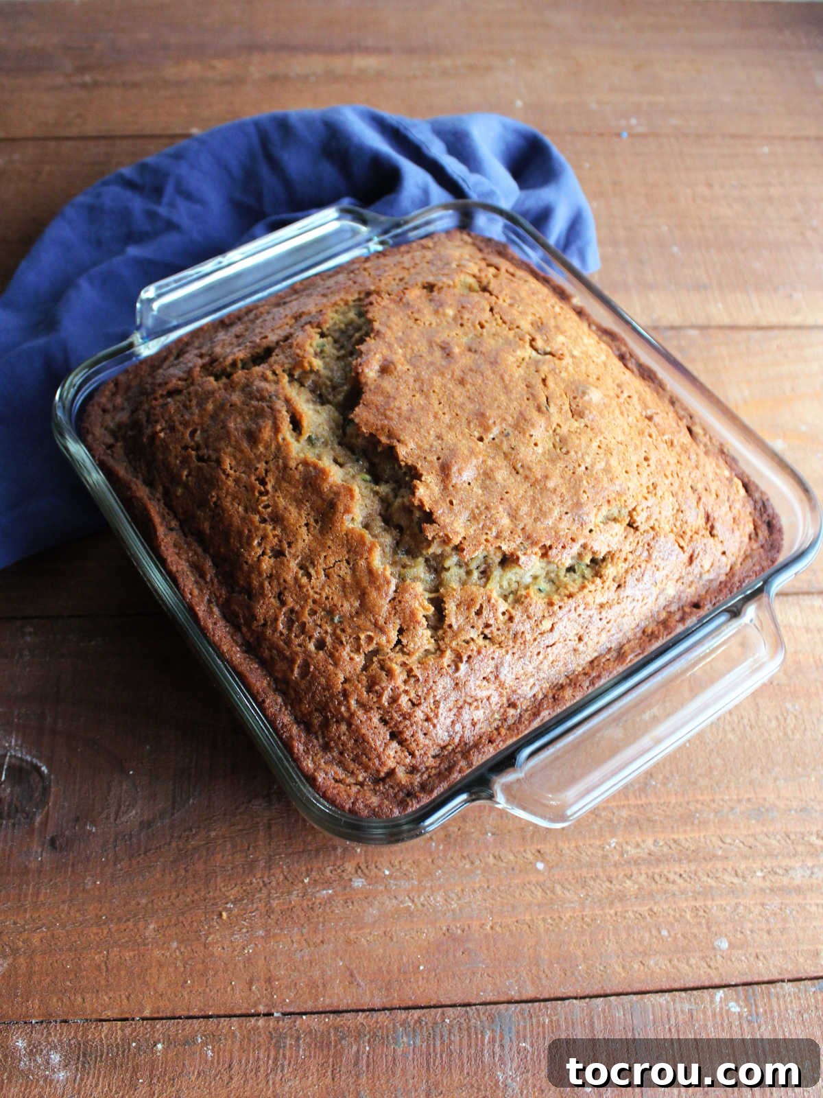 Freshly baked zucchini bread in a square baking dish, just removed from the oven, with a golden-brown top.