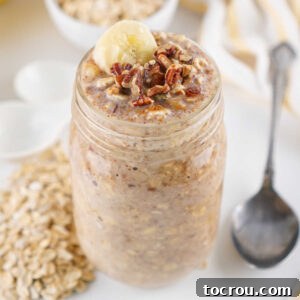 Close up of a jar of banana bread overnight oats topped with extra chopped pecans and a slice of banana, ready to eat.