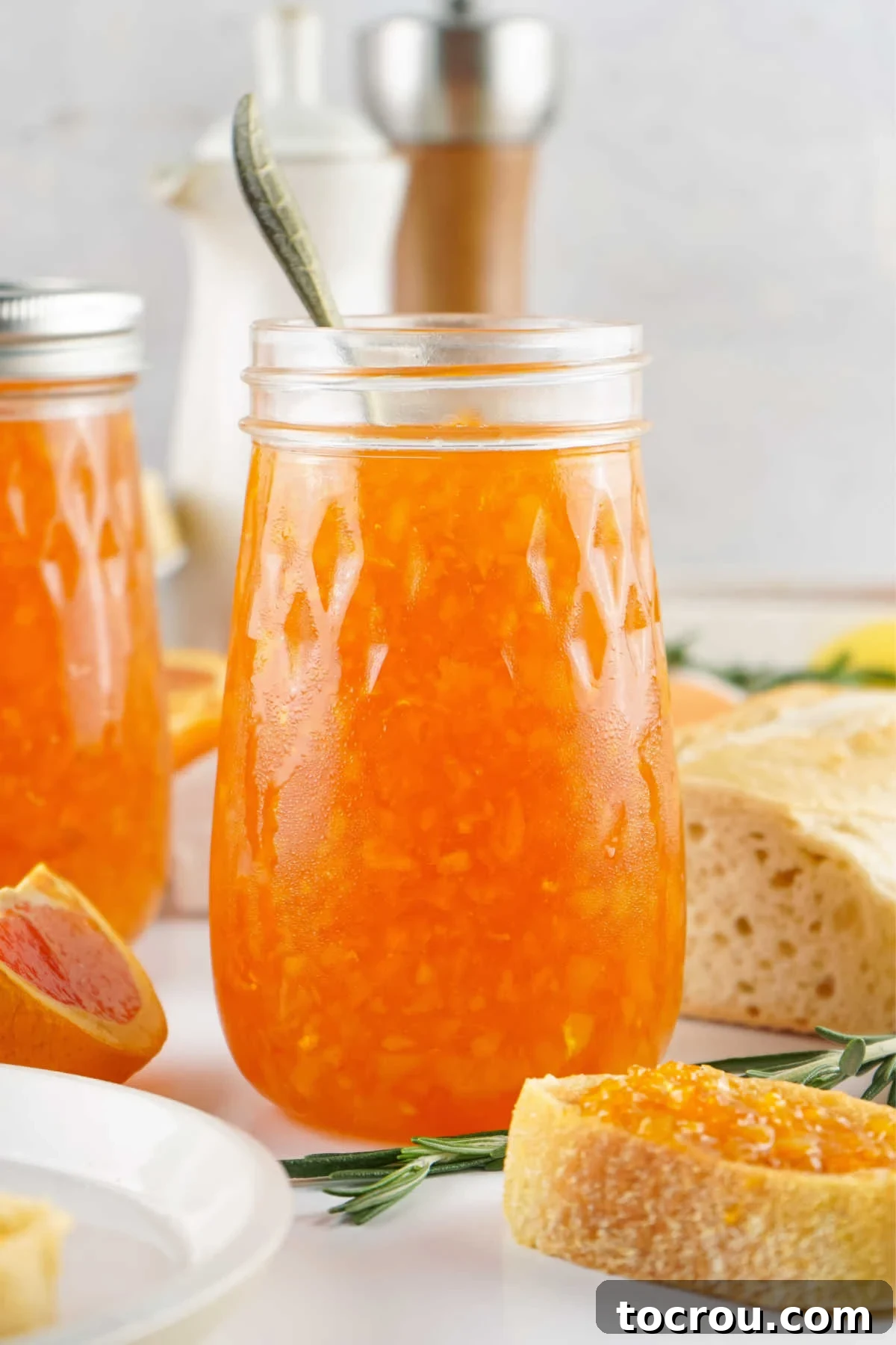 Sun-Kissed Orange Marmalade 3 Jar of homemade orange marmalade next to a slice of toast with some spread over the top.