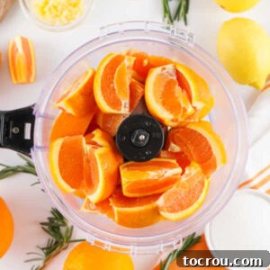 Chunks of fresh orange in a food processor, ready to be processed down.