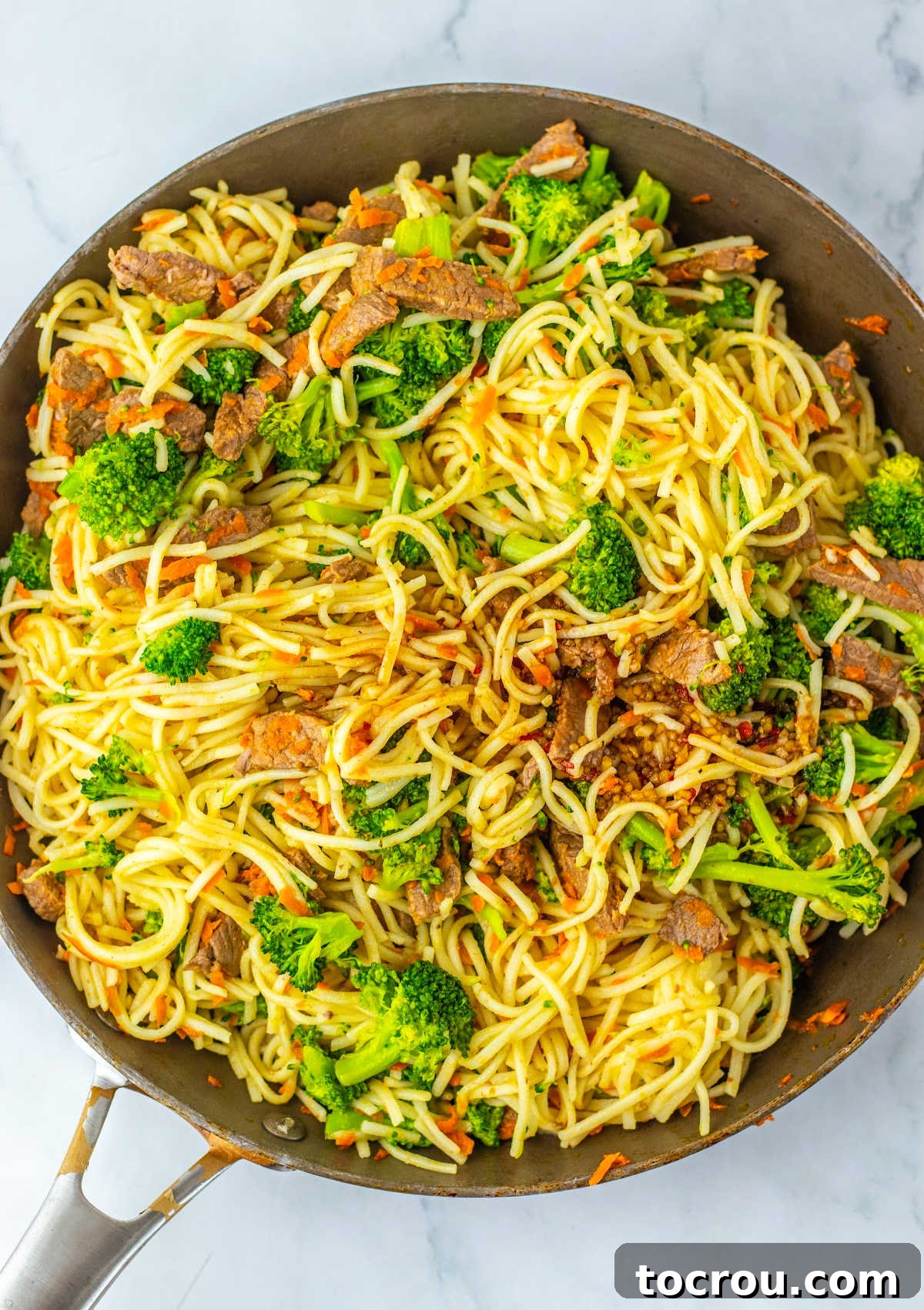 Cooking Beef and Broccoli Lo Mein in a Skillet Skillet of cooked beef and broccoli lo mein mixture, ready to be served.