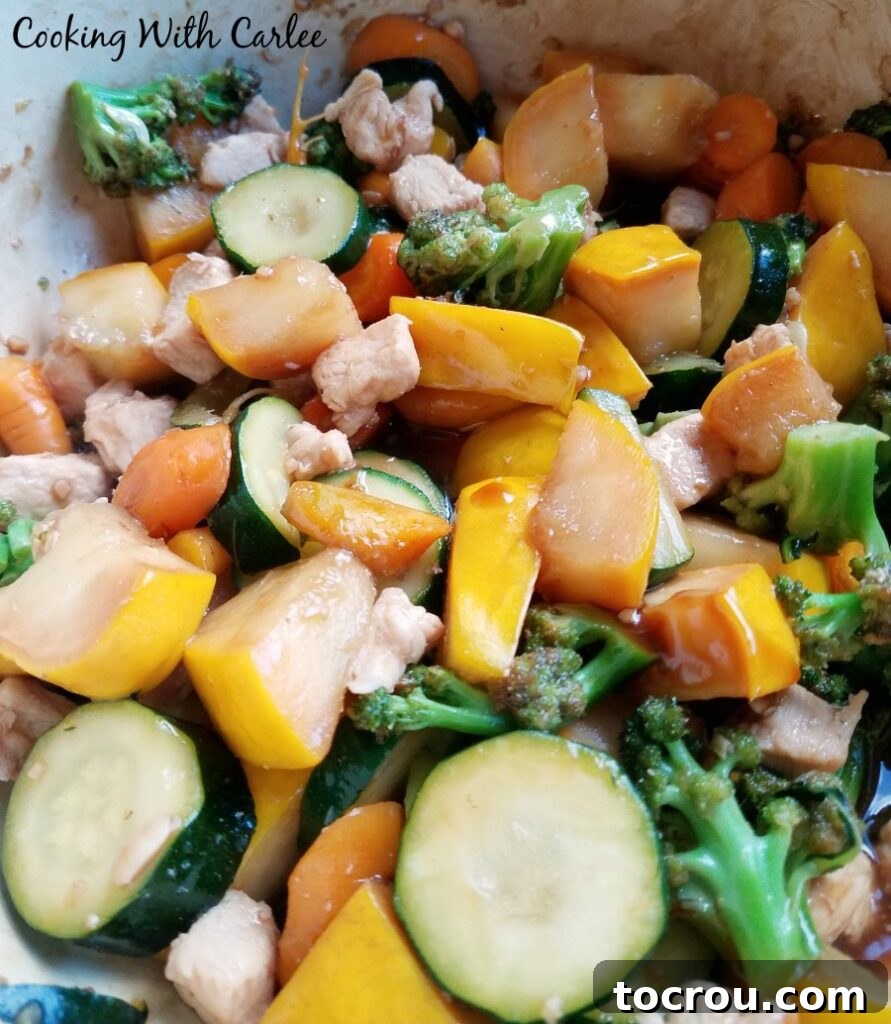 close up of chicken and veggies cooking in pan.