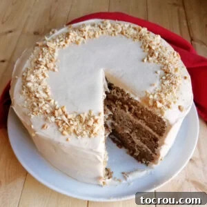 A layered applesauce cake featuring soft, creamy caramel cream cheese frosting, with a large slice missing to reveal its delicious layers.