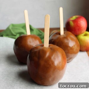Three perfectly homemade caramel apple wraps on sticks, ready to be served and enjoyed, resembling classic caramel apples.