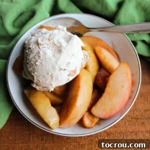 A small bowl of Crockpot Cinnamon Apples, served alongside a scoop of ice cream and a spoon, highlighting its comforting presentation.