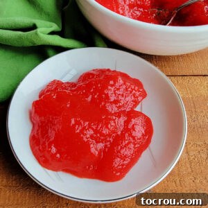 A small bowl containing a vibrant serving of bright red applesauce Jello, perfectly set and ready to eat.