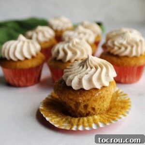 An unwrapped apple butter mini cupcake, showing its soft cake base topped with a delicate swirl of creamy apple butter frosting.