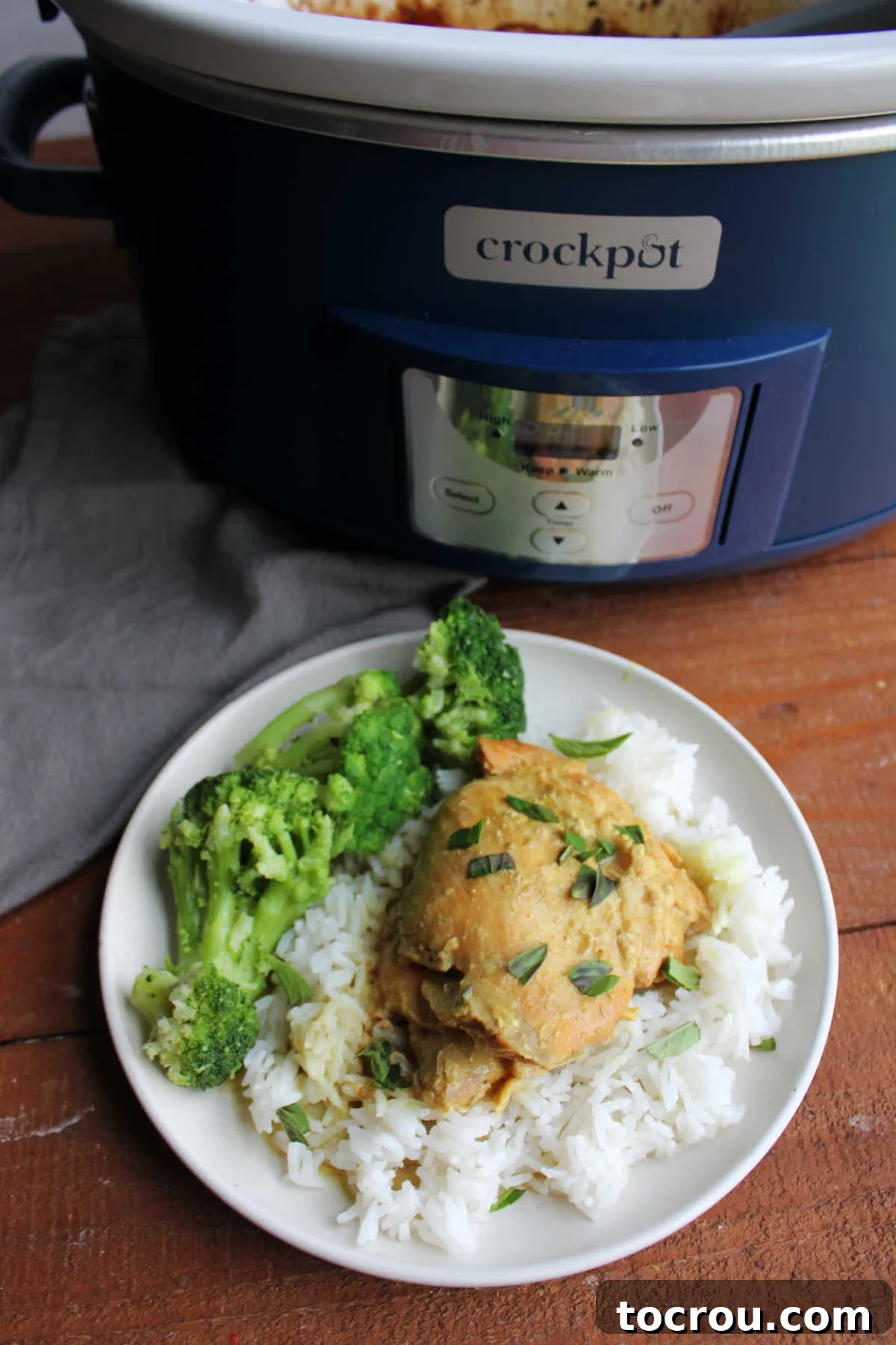 Crockpot coconut lime chicken served on a bed of rice, garnished with fresh Thai basil for a fragrant touch, ready to eat.