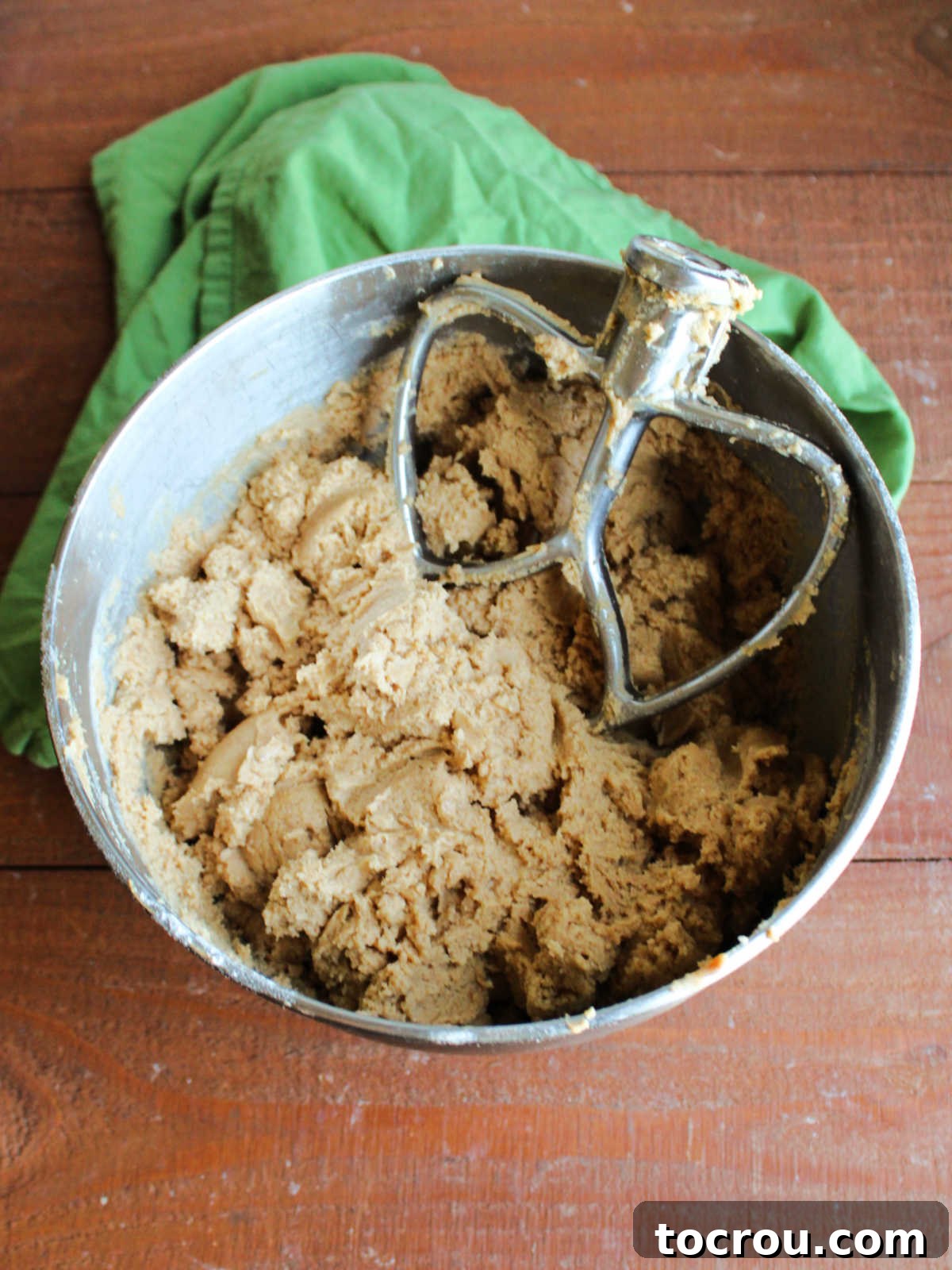 Mixer bowl filled with golden-brown sourdough peanut butter cookie dough, soft and ready to be chilled for optimal texture development.