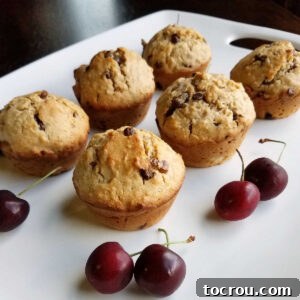 A platter of appetizing cherry chip sourdough muffins, garnished with fresh sweet cherries, ready to be enjoyed.