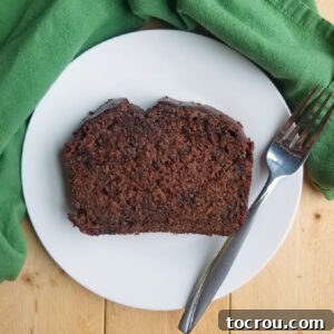 A perfect slice of sourdough chocolate banana bread on a plate with a fork, showing its moist texture and generous chocolate chunks.