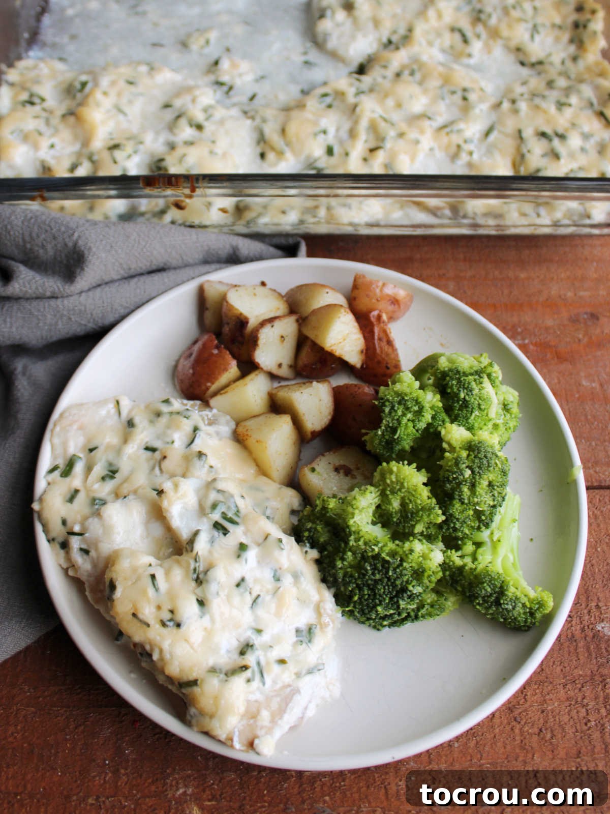 Dinner plate filled with cod topped with mayonnaise and parmesan mixture served with broccoli and cubed roasted potatoes. A complete healthy meal.