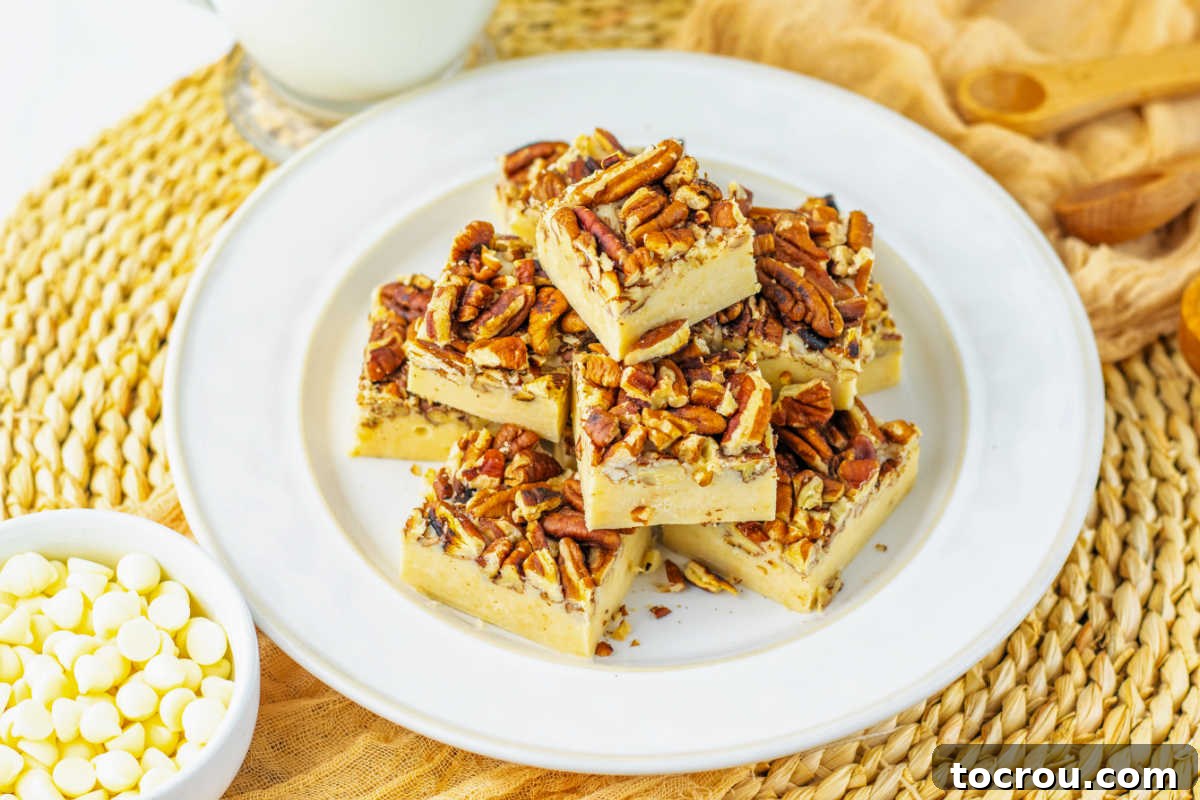 Plate of pecan pie fudge pieces with creamy fudge base and toasted pecans on top, ready to be enjoyed.