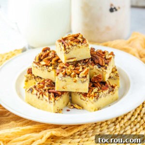 Stack of squares of pecan pie fudge with creamy base and toasted pecans on top on plate, ready to eat.