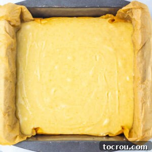 Fudge mixture spread into a parchment paper lined square baking dish.