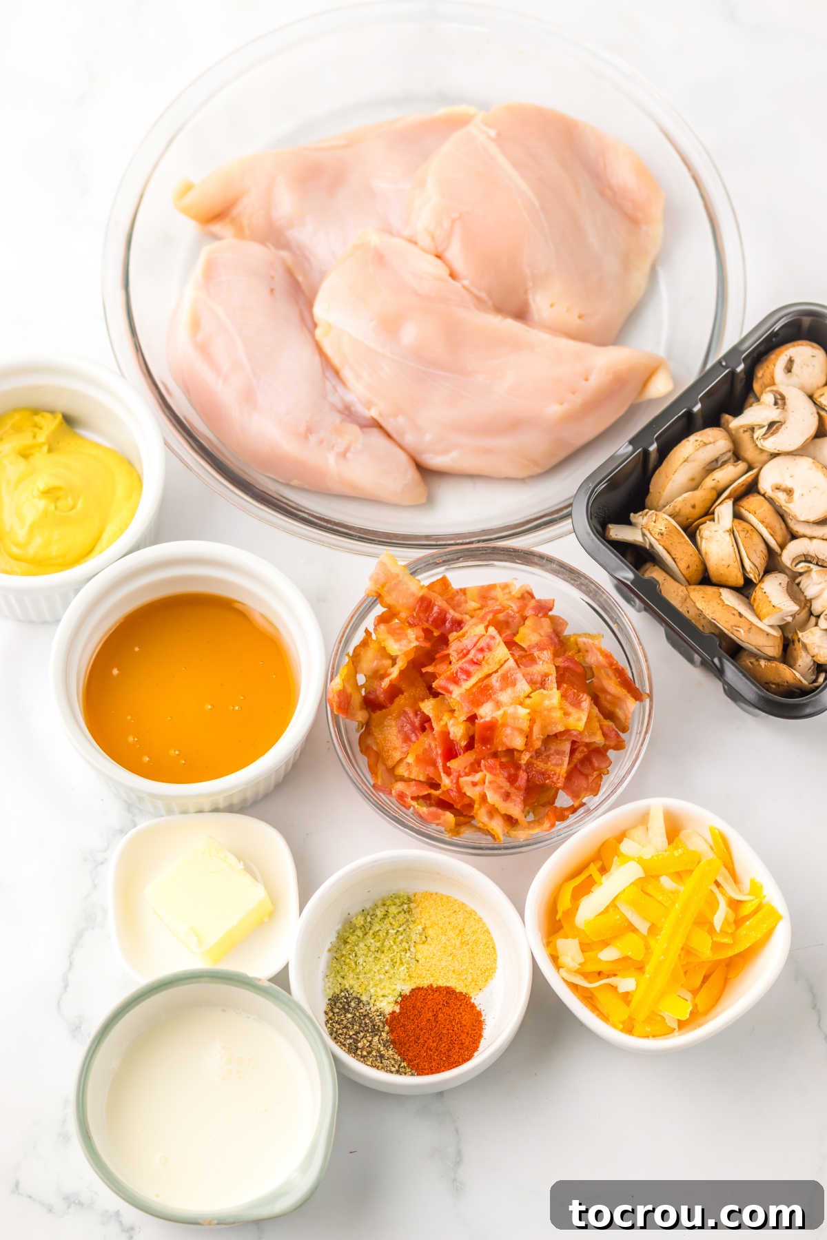 Ingredients including chicken breasts, sliced mushrooms, cooked bacon, seasonings, honey, mustard, and cheese ready to be made into crockpot alice springs chicken.