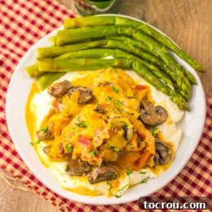 Alice springs chicken with honey mustard sauce, mushrooms, bacon and cheese served over mashed potatoes with a side of asparagus, ready to eat.