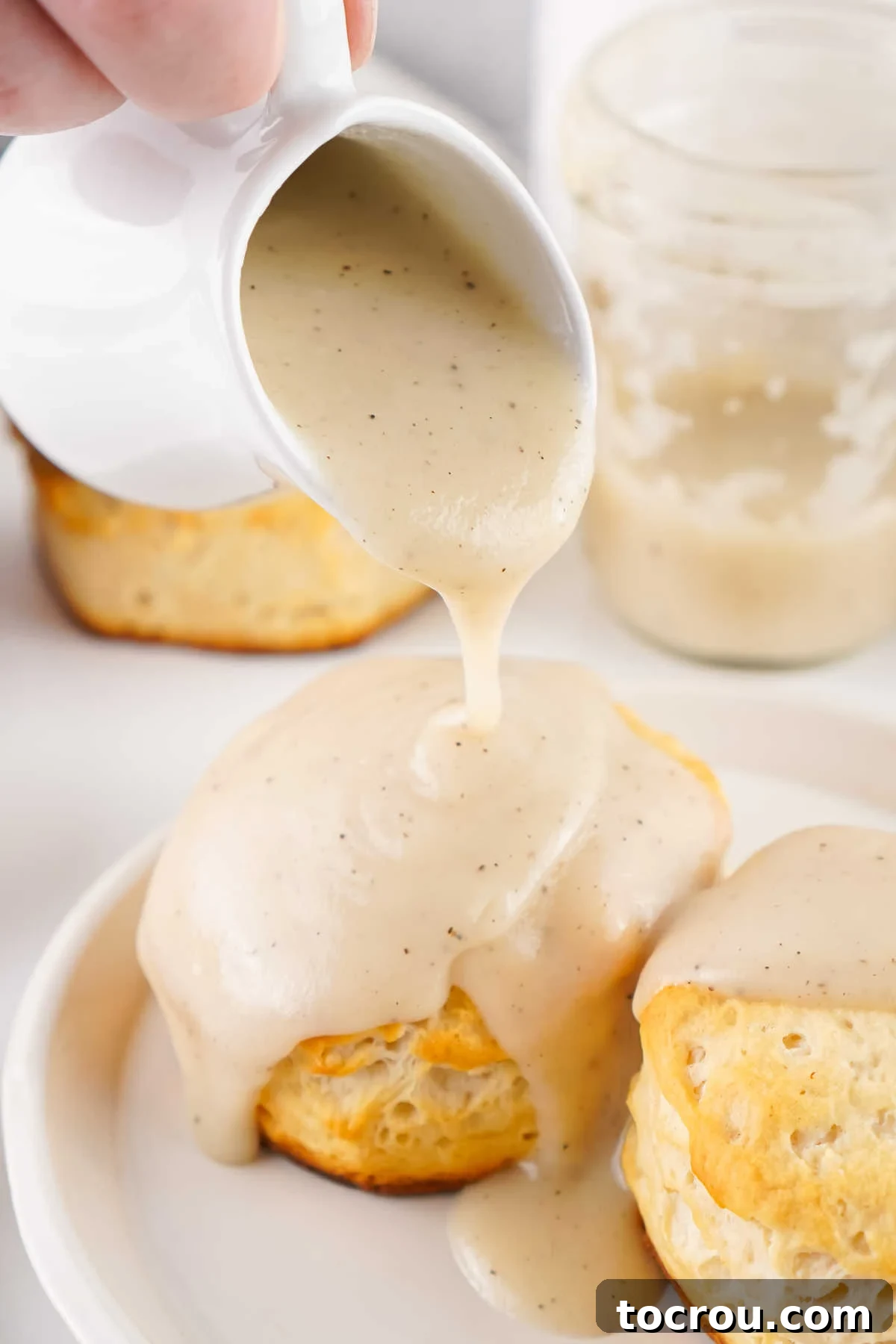 Pouring homemade milk gravy over biscuits.