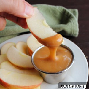 Apple slice dipped into container of homemade caramel sauce.