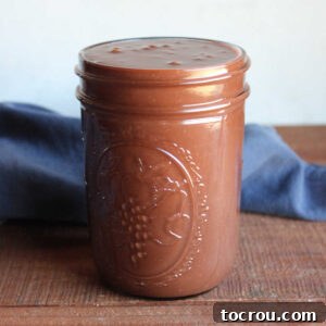 Jar of homemade hot fudge sauce made from chocolate chips, sweetened condensed milk, and butter, ready to be used.