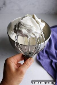hand holding beater full of cream cheese whipped cream