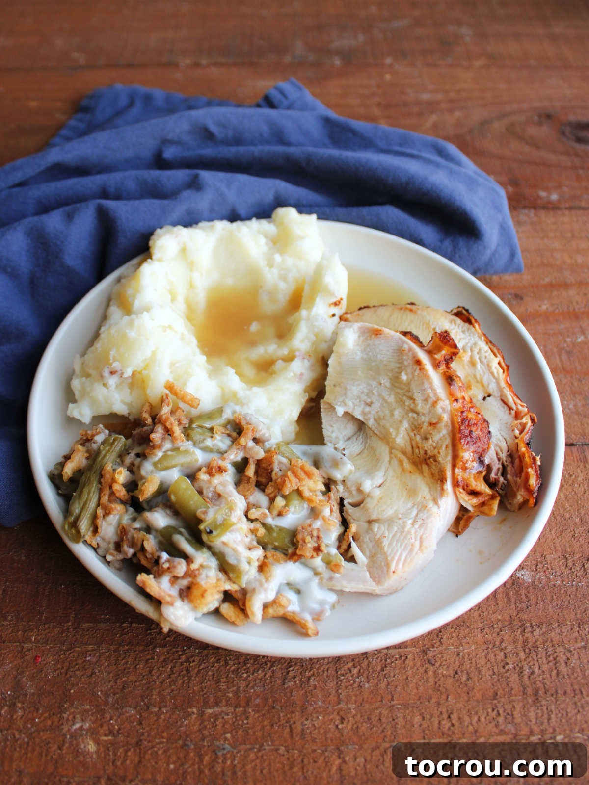 Dinner plate with smoked turkey breast slices, mashed potatoes and gravy, and green bean casserole.