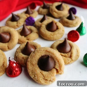 Soft peanut butter blossoms with different Kisses in the center including milk chocolate, dark chocolate, and caramel filled with some wrapped Hershey's Kisses nearby.