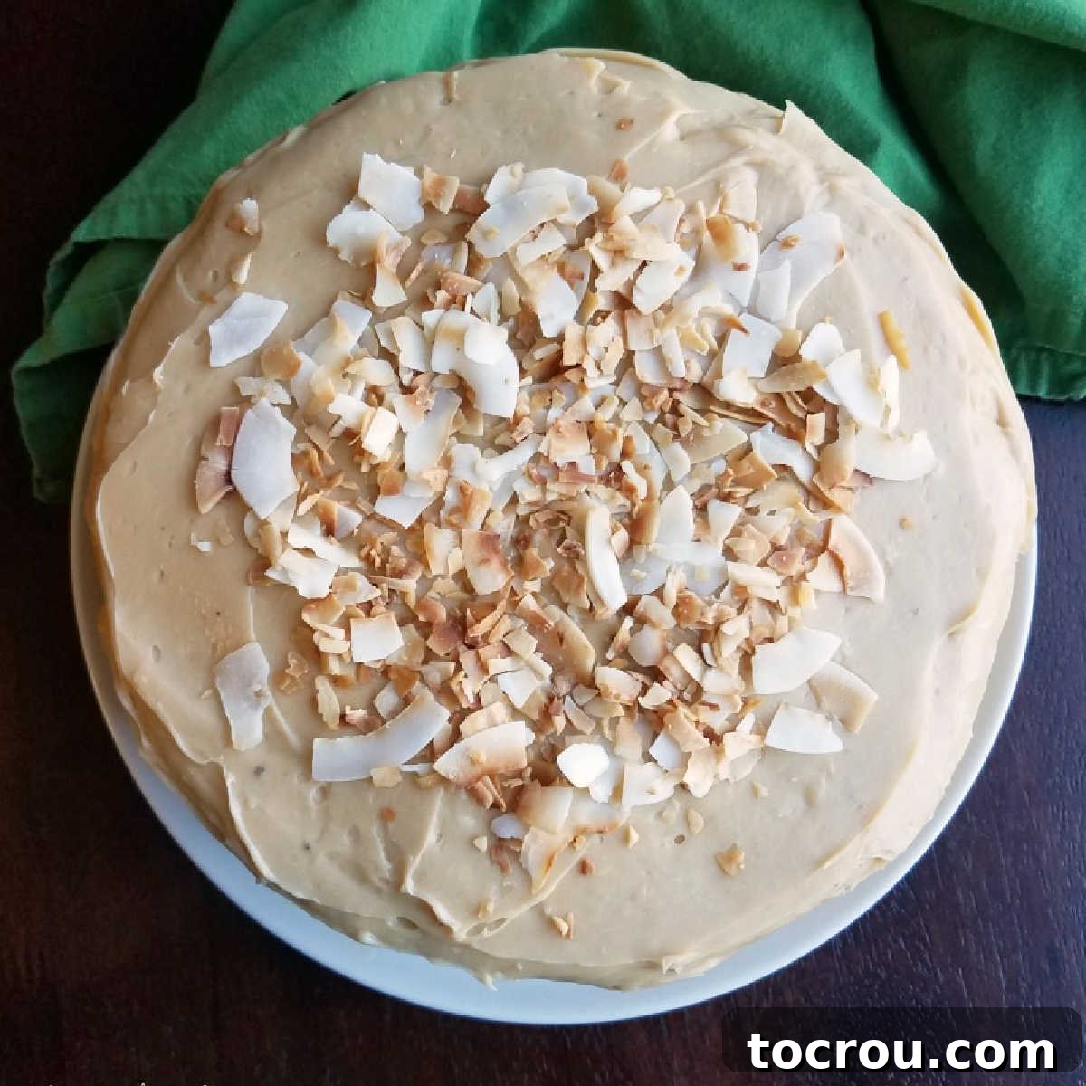 Creamy Caramel Sweetened Condensed Milk Frosting Top of round layered cake covered with creamy caramel condensed milk frosting and large flakes of coconut.