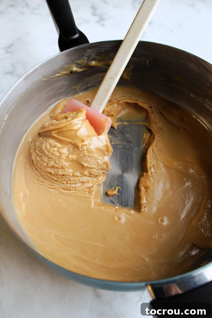 Cooked Caramel Mixture for Frosting Cooked and cooled brown sugar, butter and condensed milk mixture with spatula showing how thick it is.