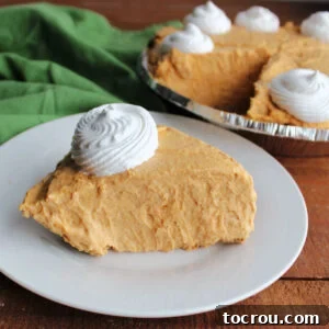 Slice of fluffy no bake pumpkin pie topped with swirl of whipped cream, ready to eat.