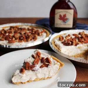 Slice of no-bake pecan cream pie with creamy maple filling topped with chopped pecans next to two pecan cream pies and a bottle of maple syrup.