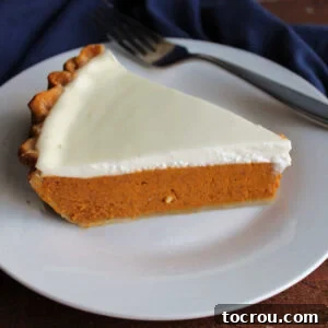 Piece of pumpkin pie with sour cream topping, ready to eat.