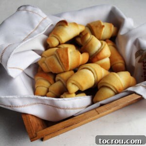 Feast Worthy Thanksgiving Sides 11 A rustic basket overflowing with freshly baked homemade crescent rolls, each boasting a buttery golden-brown exterior and a perfectly curled, classic horn shape.