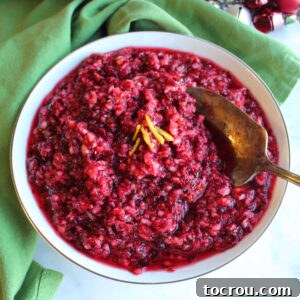 Feast Worthy Thanksgiving Sides 14 A pristine white serving bowl filled with a vibrant Fresh Orange Cranberry Relish, garnished with delicate orange zest, accompanied by a small serving spoon.