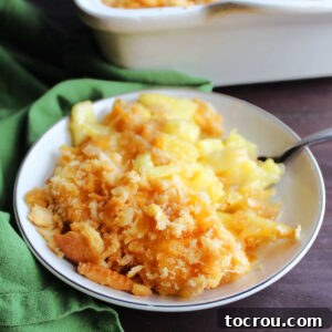 Feast Worthy Thanksgiving Sides 17 A small individual serving dish filled with golden-baked pineapple casserole, featuring a delicious topping of buttery cracker crumbs and melted cheddar cheese.
