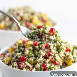 Feast Worthy Thanksgiving Sides 19 A forkful of colorful Pomegranate Couscous Salad, showcasing small, fluffy couscous grains, vibrant pomegranate arils, fresh herbs, and bright yellow bell peppers.