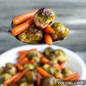 Feast Worthy Thanksgiving Sides 20 A spoonful of vibrant honey-roasted Brussels sprouts and baby carrots, glistening with a light glaze and ready to be savored as a delicious side dish.
